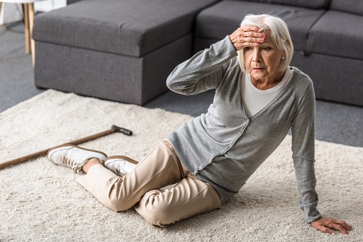 senior woman hurt on carpet and touching forehead with hand